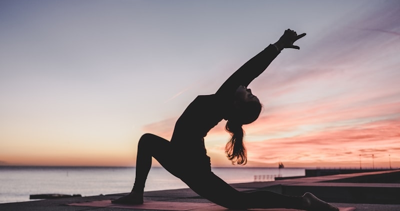 Person practicing yoga at sunset